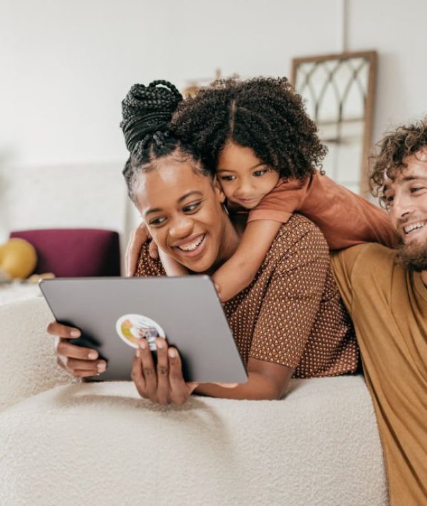 Smiling parents and daughter at home watching online movie together